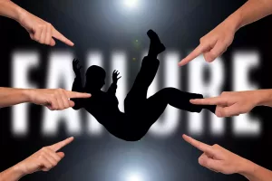 Symbolbild Scheitern, Personen zeigen mit dem Finger auf eine andere Person im freien Fall