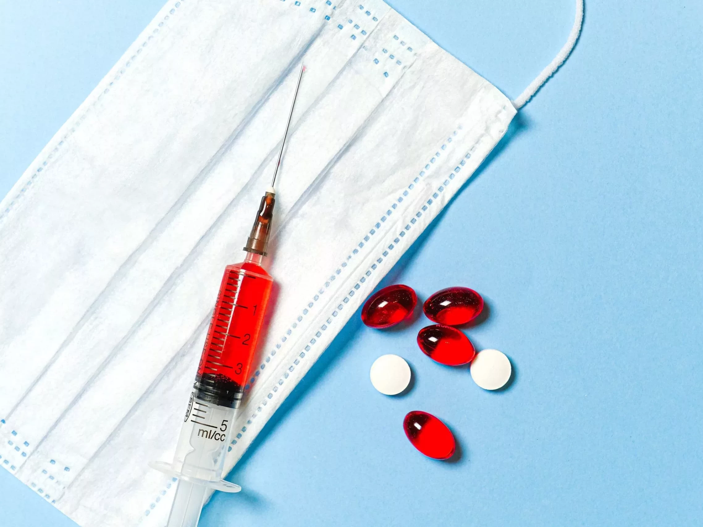 Mundschutz und Spritze und Tabletten.