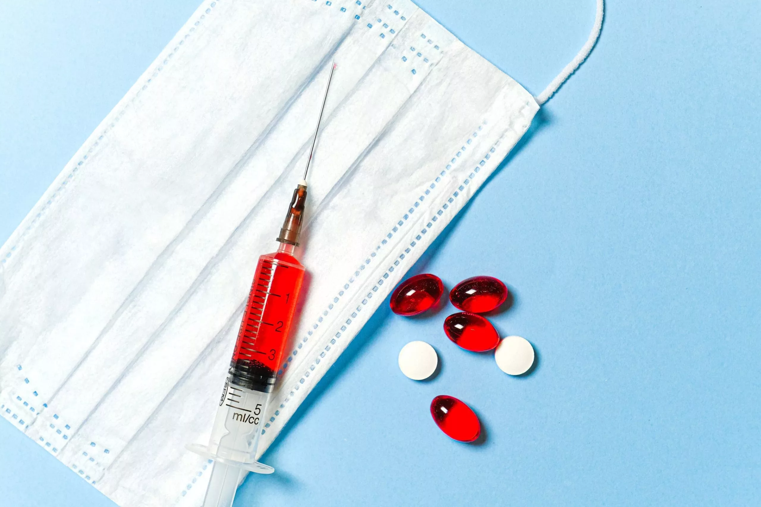 Mundschutz und Spritze und Tabletten.