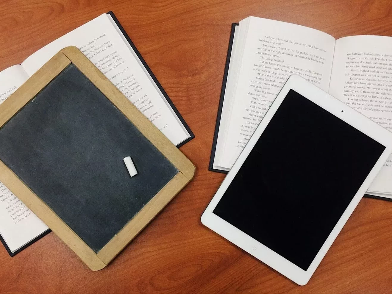 Auf dem Bild ist eine Tafel neben einem Tablet zu sehen und stellt symbolisch die digitale Bildung da.