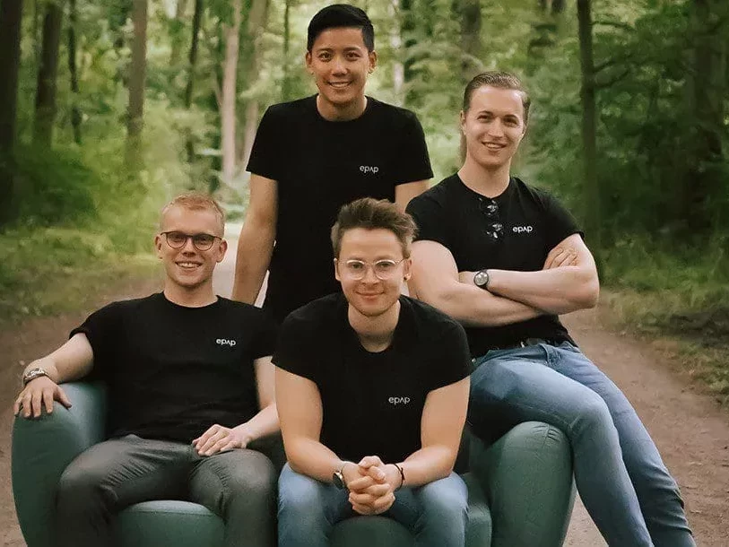 Das Bild zeigt die vier jungen Gründer vom Startup epap., die im Wald auf einem Sofa sitzen.