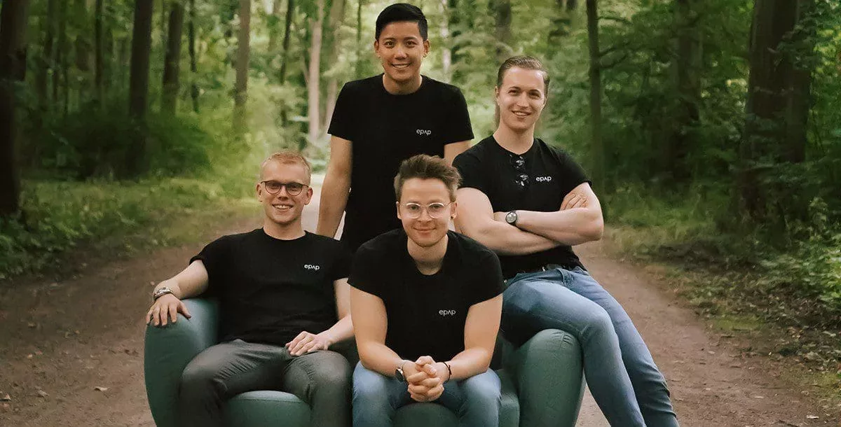 Das Bild zeigt die vier jungen Gründer vom Startup epap., die im Wald auf einem Sofa sitzen.