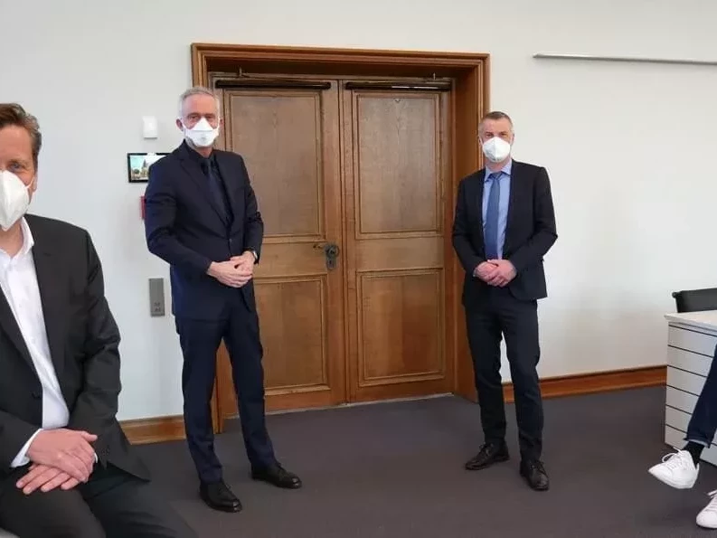 Das Bild zeigt vier Männer die mit Abstand nebeneinander stehen und einen Mundschutz tragen.
