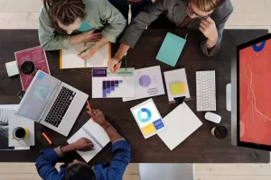 Von oben: Menschen arbeiten an einem Tisch zusammen und erheben Daten.
