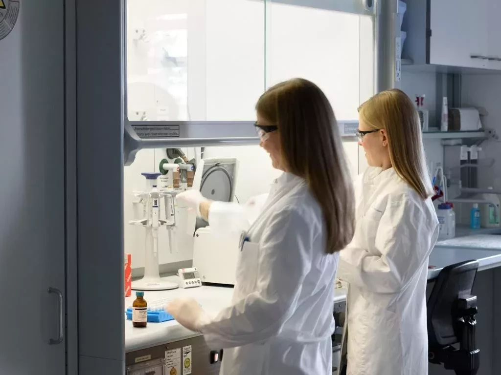 Das Bild zeigt zwei Frauen die stehend in einem Labor arbeiten.