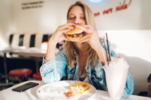 Eine Frau ist einen Burger in einem Restaurant.