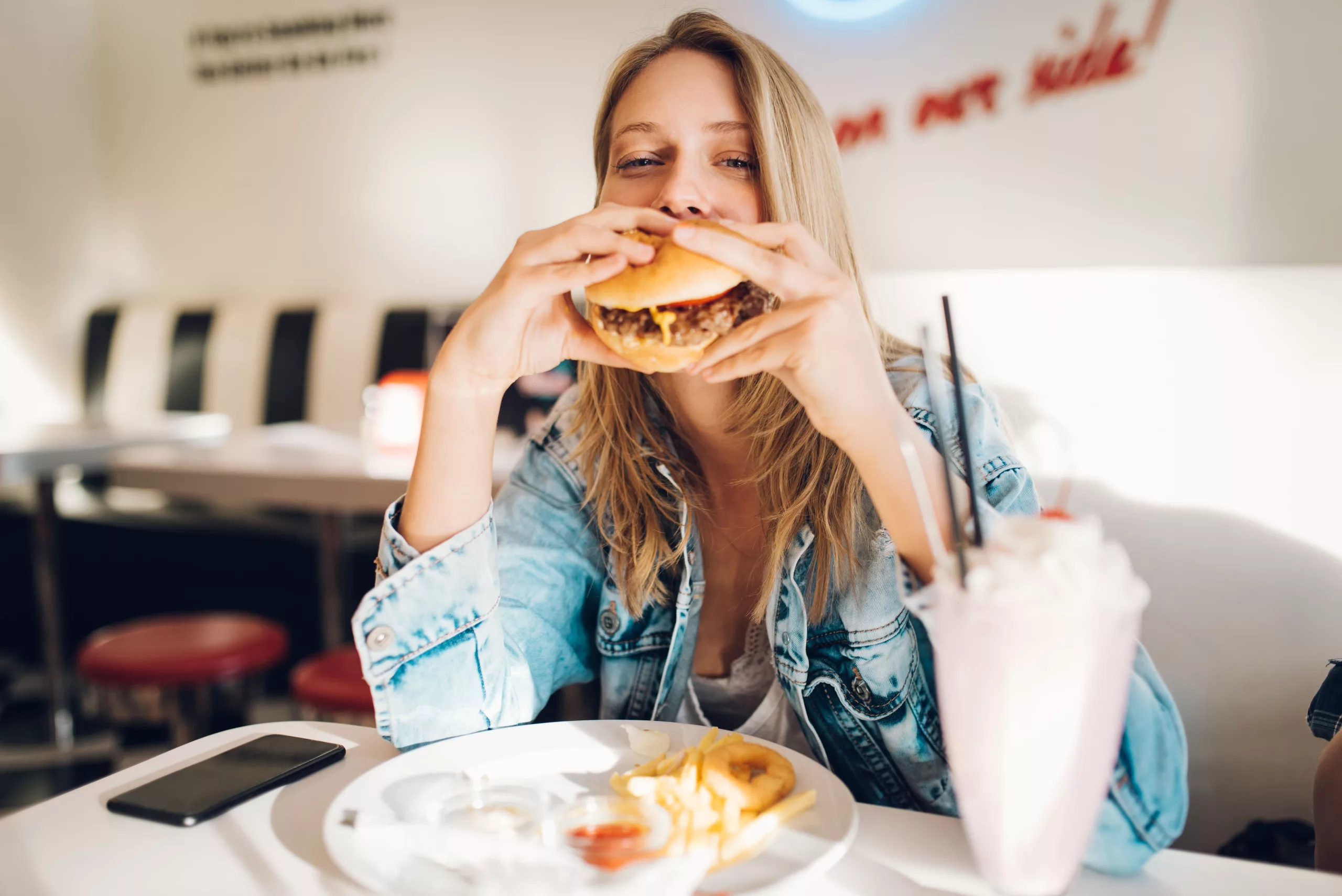 Eine Frau ist einen Burger in einem Restaurant.