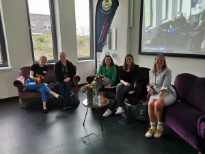 Das Bild zeigt fünf Frauen auf zwei Sofas auf einer Bühne.