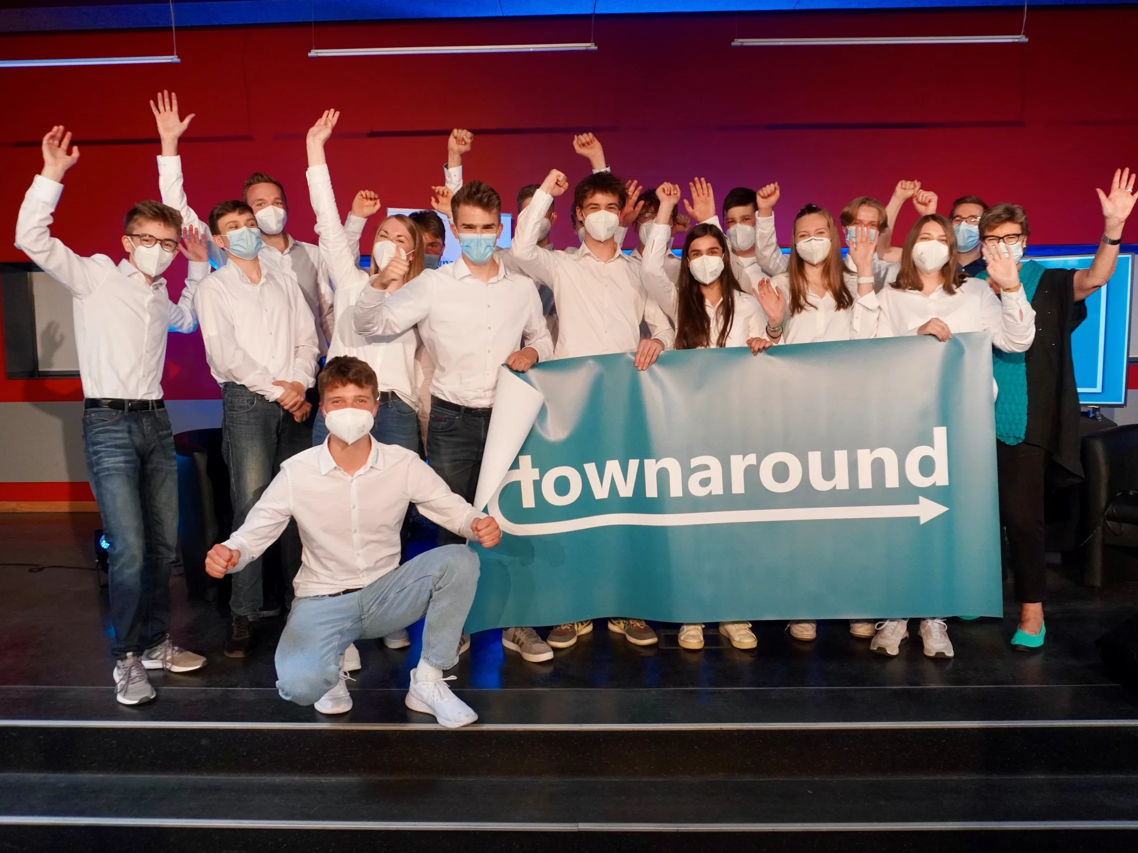 Eine Gruppe Schüler*innen feiern ihren Erfolg auf der Bühne.