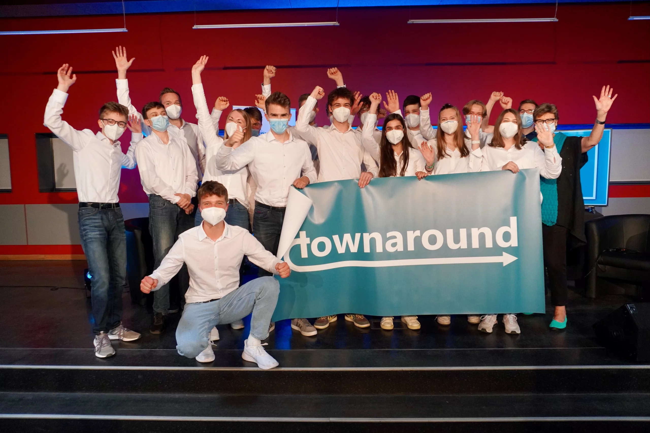 Eine Gruppe Schüler*innen feiern ihren Erfolg auf der Bühne.
