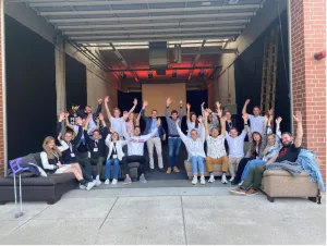 Zeigt die Gruppe der Teilnehmenden des Bootcamps in einer Garage.