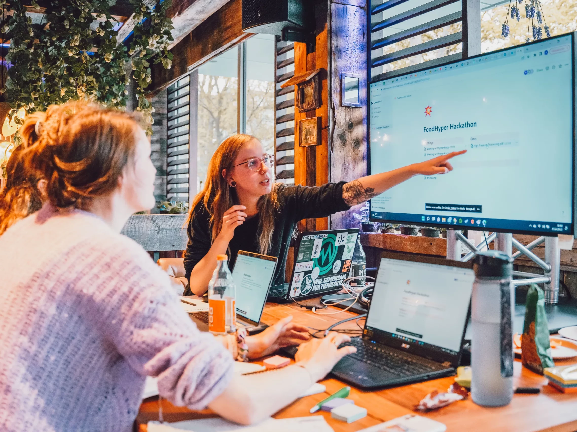 Drei Frauen vor Laptops schauen auf einen Bildschirm und besprechen sich.