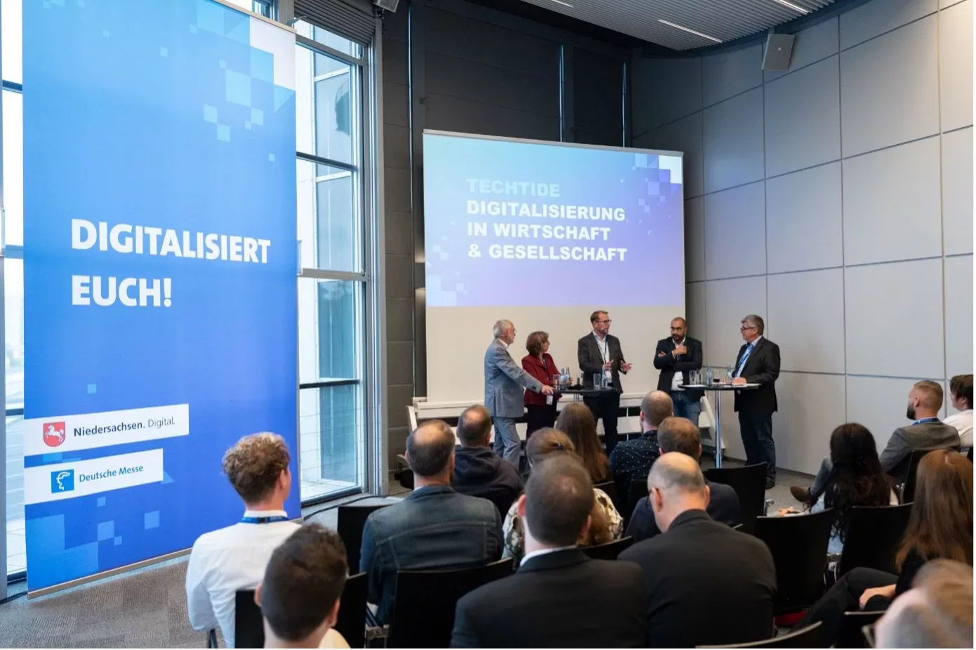 Ein Podium steht vor einem sitzendem Publikum auf der TECHTIDE.