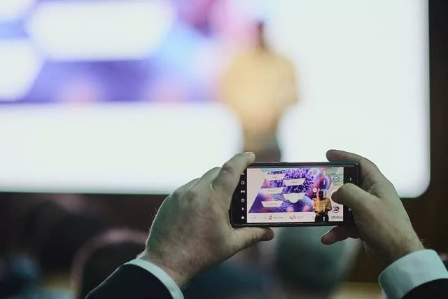 Ein Handy, dass die Bühne des Life Science Startup Days fotografiert mit dem Moderator auf der Bühne