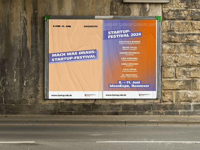 Eine Plakatwand an einer Straße mit zwei Plakaten zum Startup-Festival von Niedersachsen.next Startup. Eins ist orange mit der Aufschrift 
