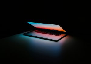 Ein halb aufgeklappter Laptop, der leuchtet im Dunkeln
