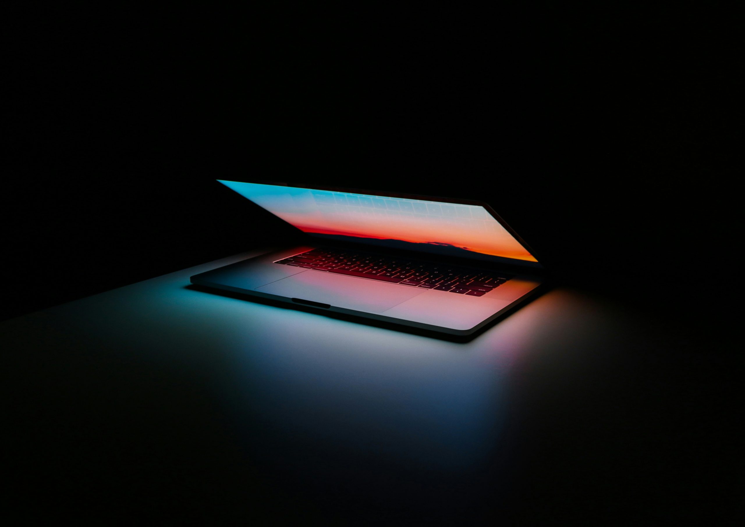 Ein halb aufgeklappter Laptop, der leuchtet im Dunkeln